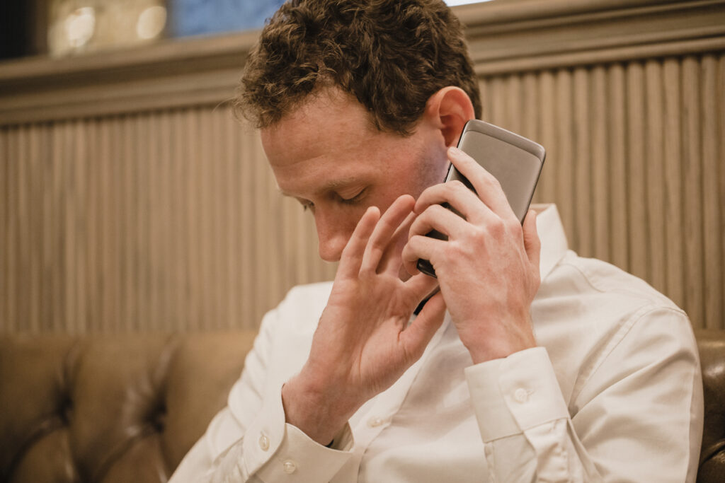  A person with a visual disability holding a smartphone close to their ear and using touch gestures while seated.
