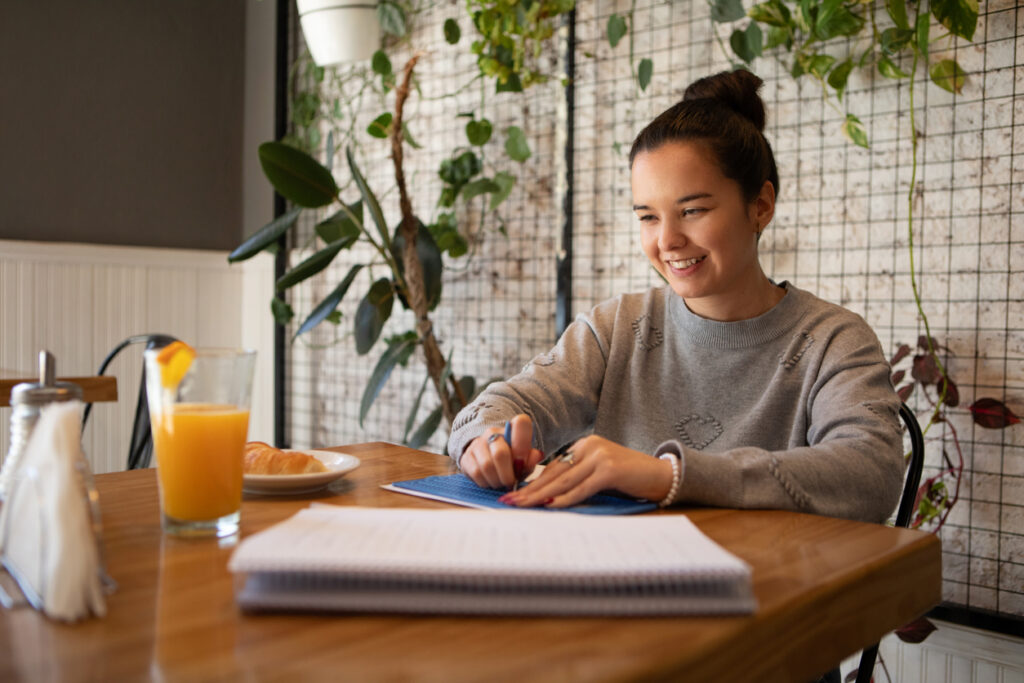 A person using a braille slate and stylus to write in a home office.